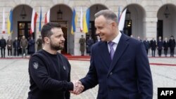 FILE - Ukraine's President Volodymyr Zelenskyy and Polish President Andrzej Duda shake hands in front of the presidential palace in Warsaw, April 5, 2023.