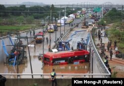 Petugas penyelamat terlihat di dekat bus listrik yang ditemukan selama operasi pencarian dan penyelamatan di dekat jalan bawah tanah yang terendam banjir akibat hujan deras di Cheongju, Korea Selatan, 16 Juli 2023. (Foto: REUTERS/Kim Hong-ji )