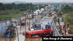 Petugas penyelamat terlihat di dekat bus listrik yang ditemukan selama operasi pencarian dan penyelamatan di dekat jalan bawah tanah yang terendam banjir akibat hujan deras di Cheongju, Korea Selatan, 16 Juli 2023. (Foto: REUTERS/Kim Hong-ji )