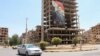 (FILE) Vehicles pass near a poster depicting Syria's President Bashar al-Assad in Douma, Syria.