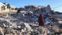 Ibu Ahmed Dawabsha berjalan di atas reruntuhan rumahnya di desa Duma di Tepi Barat yang diduduki Israel, 3 Juli 2024, setelah rumah tersebut dihancurkan oleh tentara Israel yang menangkap putranya pada bulan April atas pembunuhan seorang remaja Israel. (Zain JAAFAR/AFP)