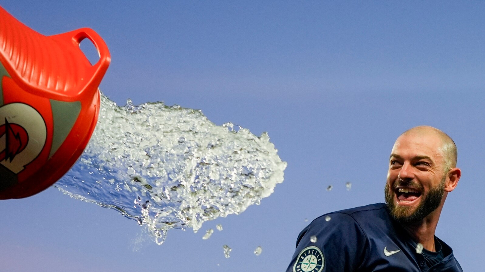Seattle Mariners' Mitch Haniger tries to avoid a dousing during the celebration of the team's 2-1 win over the Chicago White Sox in 10 innings in a baseball game, June 12, 2024, in Seattle. Haniger drove in the winning run. 