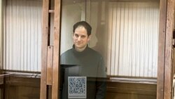 Wartawan Wall Street Journal, Evan Gershkovich, berdiri di dalam kurungan kaca di ruang persidangan di Pengadilan Kota Moskow, pada 20 Februari 2024. (Foto: Moscow City Court via AP)