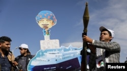 A Houthi follower holds a rocket launcher as others carry a cutout banner portraying the Galaxy Leader cargo ship that was seized by the Houthis, during a parade as part of a "popular army" mobilization campaign in Sanaa, Yemen, on Feb. 7, 2024.