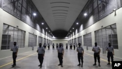 FILE - Prison guards stand outside holding cells at the Terrorism Confinement Center, a new "mega-prison" built especially for gang members, during a media tour in Tecoluca, El Salvador, Feb. 2, 2023.