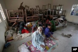 Families take shelter in a school after fleeing from their villages of coastal areas due to Cyclone Biparjoy approaching, in Gharo near Thatta, Pakistan, June 14, 2023.