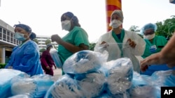 FILE - Health care workers line up for free personal protective equipment in front of murals by artist Romero Britto at Jackson Memorial Hospital, Sept. 22, 2020, in Miami. 