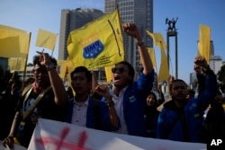 Para pengunjuk rasa meneriakkan slogan-slogan sambil mengibarkan bendera kuning yang biasanya digunakan untuk melambangkan duka selama aksi unjuk rasa menuntut pemilihan presiden yang adil di Jakarta, 12 Februari 2024. (AP/Dita Alangkara)