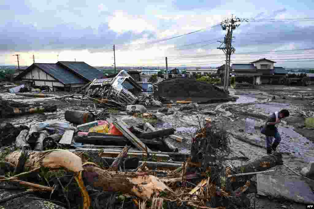 A man walks past debris in the road in the city of Kurume, Fukuoka prefecture after heavy rains hit wide areas of Kyushu island.