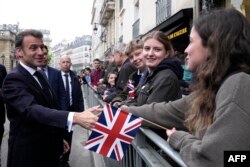 French President Emmanuel Macron shakes hands with onlookers gathered outside the Elysee Palace in Paris, April 8, 2024.