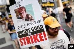 A sign disparaging artificial intelligence technology is carried while striking writers and actors walk a picket line in New York, July 17, 2023.