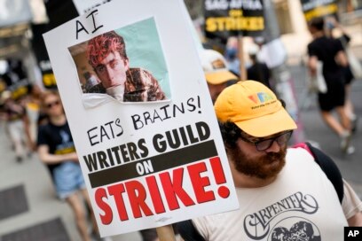 A sign disparaging artificial intelligence technology is carried while striking writers and actors walk a picket line in New York, July 17, 2023.