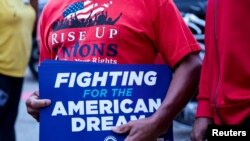 FILE: Seorang anggota serikat pekerja Unit,ed Auto Workers memegang tanda di luar Pabrik Perakitan Stellantis Sterling Heights, menandai dimulainya negosiasi kontrak di Sterling Heights, Michigan, AS 12 Juli 2023. (REUTERS/Rebecca Cook)