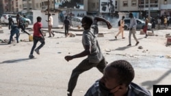 A protester throws stones during clashes with police on the sidelines of a protest against a last-minute delay of presidential elections in Dakar on February 9, 2024.