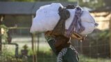 FILE - A woman carries her belongings as she flees amid fighting between the army and paramilitaries in Khartoum on April 19, 2023