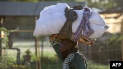 FILE - A woman carries her belongings as she flees amid fighting between the army and paramilitaries in Khartoum on April 19, 2023