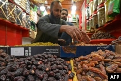 Seorang penjaga toko yang menjual kurma menunggu pelanggan di sebuah pasar di Srinagar, 22 Maret 2023, saat orang membeli bahan makanan untuk persiapan menjelang bulan suci Ramadan. (TAUSEEF MUSTAFA/AFP)