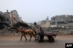 FILE - A man rides a horse-pulled cart along a street ravaged by Israeli bombing in Rafah in the southern Gaza Strip on Feb. 9, 2024.