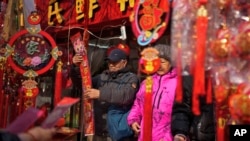 大衆在北京街邊小攤購買對聯等年貨。 （2024年2月9日）