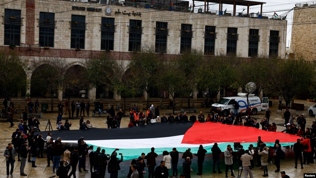 Warga membentangkan bendera Palestina di Manger Square di dekat Gereja Kelahiran Yesus di Bethlehem, Tepi Barat, pada 24 Desember 2023. (Foto: Reuters/Clodagh Kilcoyne)