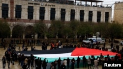 Warga membentangkan bendera Palestina di Manger Square di dekat Gereja Kelahiran Yesus di Bethlehem, Tepi Barat, pada 24 Desember 2023. (Foto: Reuters/Clodagh Kilcoyne)