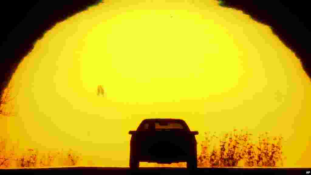 Siluet sebuah mobil yang melaju menjelang matahari terbenam, pada malam vernal equinox (di mana posisi matahari tepat di atas garis khatulistiwa), di kota Shawnee, Kansas, 19 Maret 2023. (AP)&nbsp;