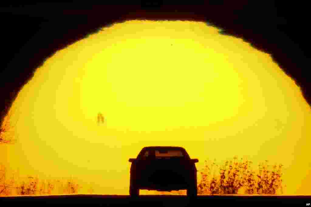 A motorist is silhouetted against the setting sun on the eve of the vernal equinox, March 19, 2023, in Shawnee, Kansas.