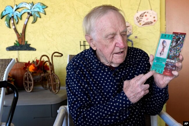 Tom Henschel holds up tickets to quarterback Tom Brady's first and last Super Bowl games during an interview at his home, in Tampa, Florida, Jan. 25, 2024.