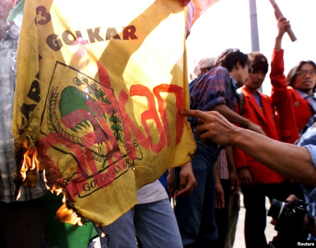 Mahasiswa memegang bendera Partai Golkar yang dibakar dengan tulisan "bubarkan Golkar" saat demonstrasi di Jakarta 18 Mei 1999 usai reformasi. (Foto: Reuters)