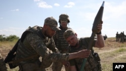 Ukrainian servicemen manipulate a rocket launcher during a training exercise not far from front line in the Donetsk region, June 8, 2023.