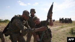 Ukrainian servicemen manipulate a rocket launcher during a training exercise not far from front line in the Donetsk region, June 8, 2023.