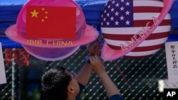 Seorang pedagang menyiapkan makanan dan minuman di stan yang menampilkan planet berbentuk bendera China dan Amerika selama Karnaval Musim Semi di Beijing pada 13 Mei 2023. (Foto: AP)