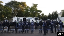 FILE - South African Police Service officers line up near temporary dwelling built by foreign migrants in front of the United Nations High Commissioner for Refugees offices in Pretoria on April 21, 2023 ahead of a forced eviction.