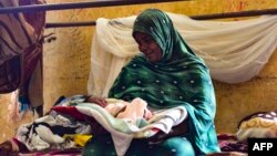 FILE - A woman, displaced by Sudan's conflict, cares for a baby at a makeshift shelter, in al-Hasahisa, south of Khartoum, July 8, 2023.