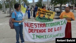 La guatemalteca Lucía Quié (derecha) posa junto a sus hijas portando un cartel que reza "nuestra economía depende de los inmigrantes" durante la marcha organizada en este sábado 1 de julio en Homestead, Florida, contra la ley SB 1718.