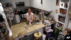 Amanda Morian washes dishes in her home in Denver's Globeville neighborhood, July 24, 2023. Morian has a 13-week-old baby.