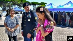 Yoko Sakato, left, and Valerie Matsunaga, right, relatives of soldiers who fought in the 442nd Infantry Regiment during World War II, are flanked by U.S. Army Staff Sgt. Michael A. Rosado, at Camp Darby, Tuscany, Italy, July 11, 2024.