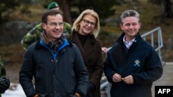 Swedish Prime Minister Ulf Kristersson is pictured with Defense Minister Pal Jonson and Finance Minister Svantesson during a military demonstration as a new support package for Ukraine is presented, Feb. 20, 2024, at Berga Naval Base, south of Stockholm.