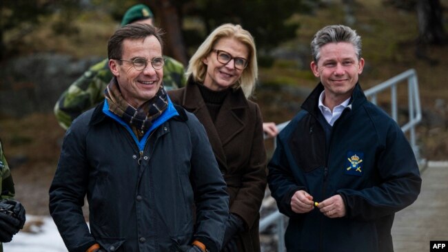 Swedish Prime Minister Ulf Kristersson is pictured with Defense Minister Pal Jonson and Finance Minister Svantesson during a military demonstration as a new support package for Ukraine is presented, Feb. 20, 2024, at Berga Naval Base, south of Stockholm.