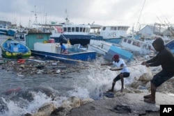 Fishermen pull a boat damaged by Hurricane Beryl back to the dock at the Bridgetown Fisheries in Barbados, July 1, 2024. (AP Photo/Ricardo Mazalan)
