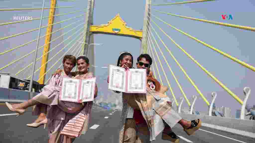 Dos parejas posan tras recibir su licencia de matrimonio en San Valentín en un puente paralelo al Puente Rama IX, en Tailandia. [Reuters]