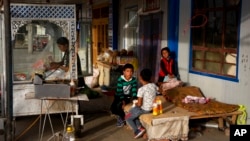 FILE - A Uyghur woman works while her children play in Hotan, in western China's Xinjiang region, Sept 20, 2018. U.S. trade figures show that as of October 2024, Southeast Asia is being hit hardest by U.S. trade restrictions on exports believed to come from Uyghur forced labor.