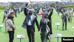 A person looks at a statue of former president Nelson Mandela and his wife Winnie Madikizela-Mandela at a tourist spot named The Long March to Freedom, Cape Town, South Africa, July 18, 2023.