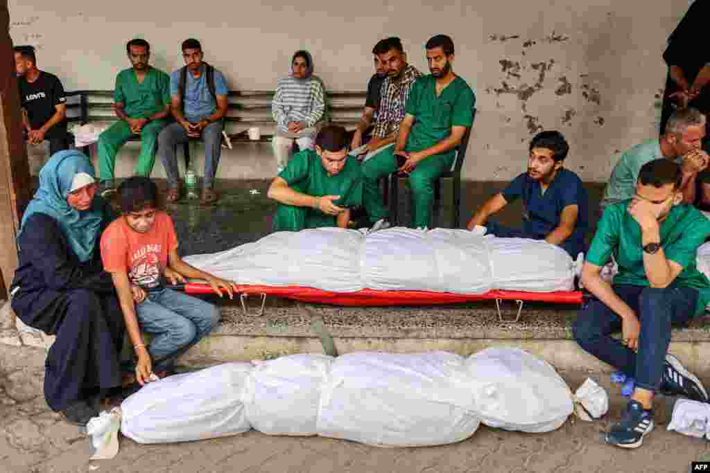 Medical staffers at the Ahli Arab Hospital mourn by the shrouded body of their colleague, a nurse who was killed during Israeli bombardment the previous night at the Shati refugee camp, at the hospital premises in Gaza City. (Photo by Omar AL QATTA / AFP)