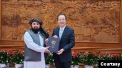 在塔利班提供的这张照片中，新任命的塔利班大使卡里米2023年12月1日在北京向中国外交部礼宾司司长洪磊递交国书副本。
