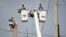 ARCHIVO - Obreros reparan cables eléctricos dañados por el huracán María en la comunidad Cantera en San Juan, Puerto Rico, el 19 de octubre del 2017. Actualmente la isla sufre de apagones crónicos en medio de advertencias de calor excesivo.
