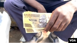 A vendor who requested that his face not be shown holds bills of Zimbabwe's outgoing currency, in Harare, April 15, 2024. (Columbus Mavhunga/VOA)