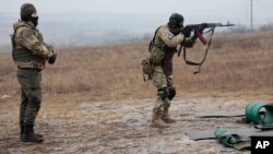 FILE - A Russian army soldier shoots as an instructor stands near during a practice on a military training ground in Russian-controlled Donetsk region, eastern Ukraine, Jan. 31, 2023.