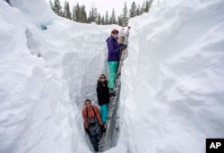Working on behalf of the UC Berkeley Central Sierra Snow Lab, Shaun Joseph, Claudia Norman and Helena Middleton take measurements ahead of a weather storm on March 9, 2023, in Soda Springs, Calif. (Karl Mondon/Bay Area News Group via AP, File)