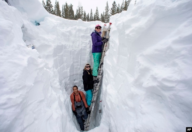 Working on behalf of the UC Berkeley Central Sierra Snow Lab, Shaun Joseph, Claudia Norman and Helena Middleton take measurements ahead of a weather storm on March 9, 2023, in Soda Springs, Calif. (Karl Mondon/Bay Area News Group via AP, File)